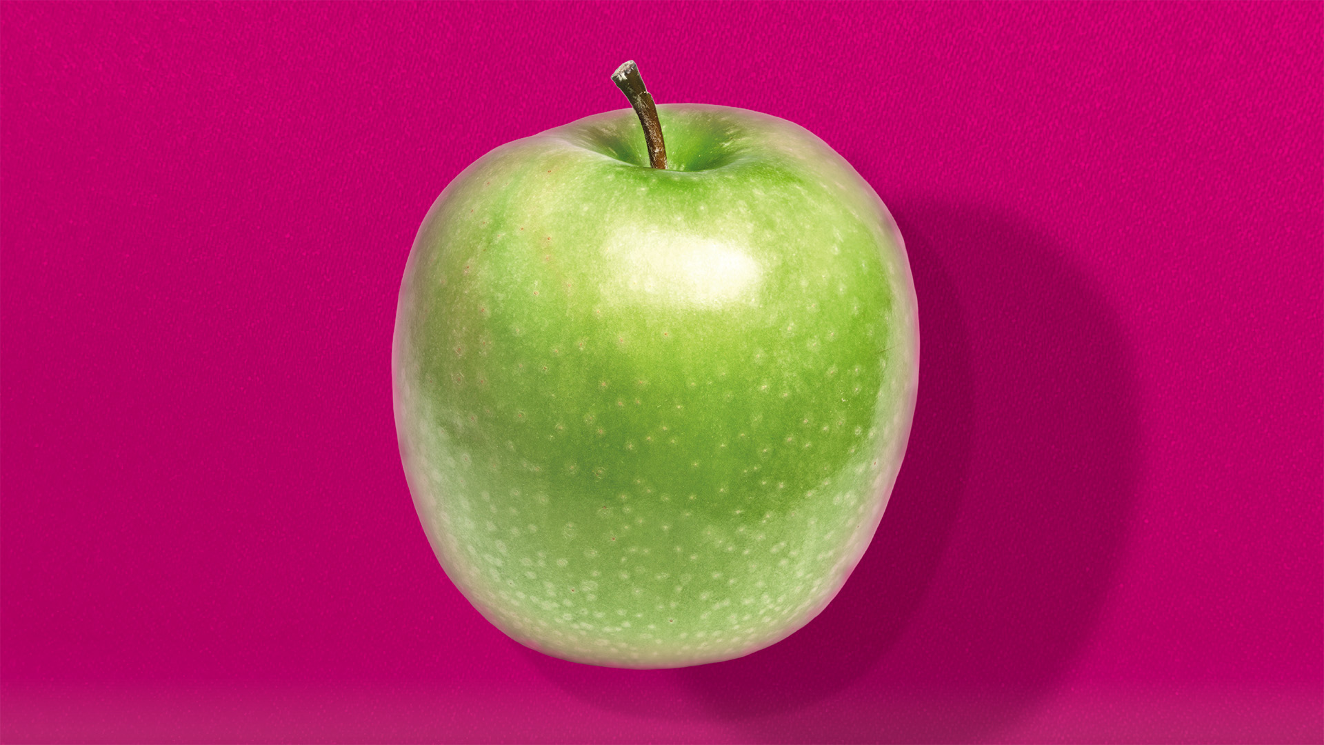 Ein Apfel vor einem pinken Hintergrund