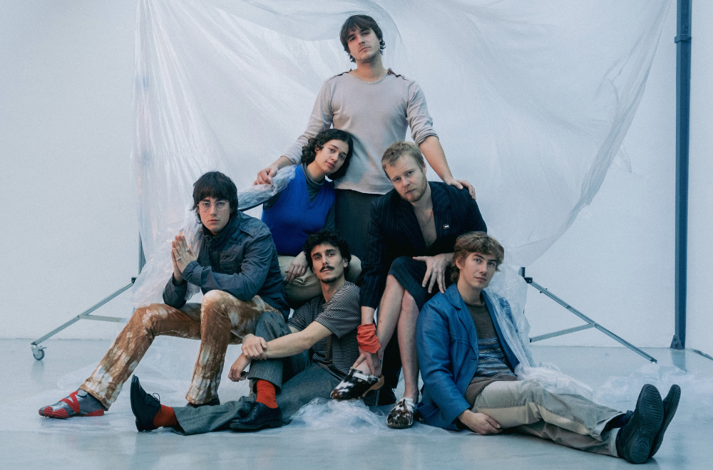 Portrait der Band Buntspecht. Sitzen und stehen vor einer Plane.