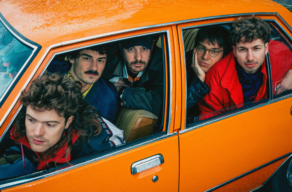 Die Band Von Wegen Lisbeth sitzt in einem orangenen Auto