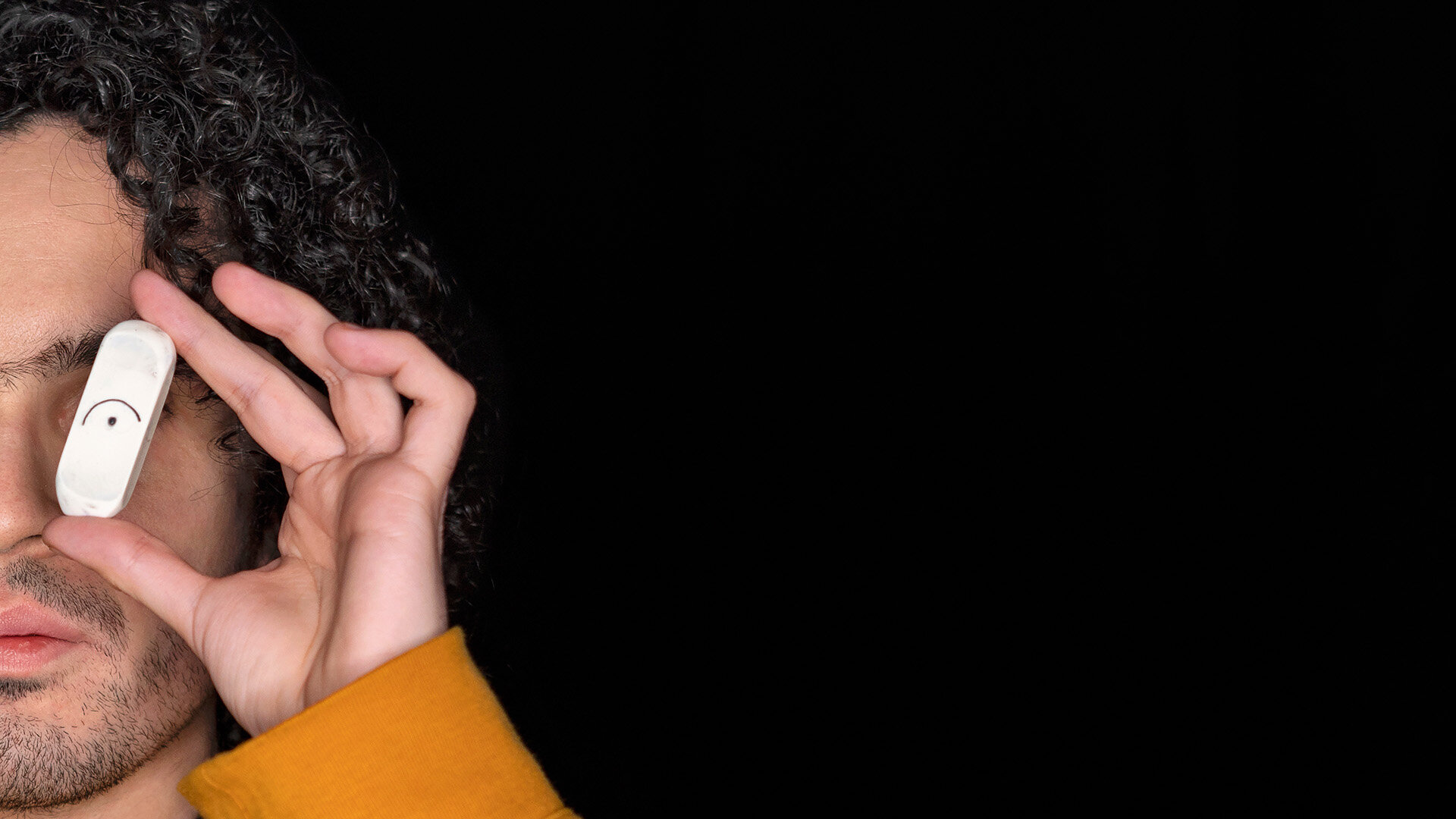 Ein Radiergummi mit aufgemaltem Auge wird vor dem Auge eines männlichen Halbgesichts gestellt