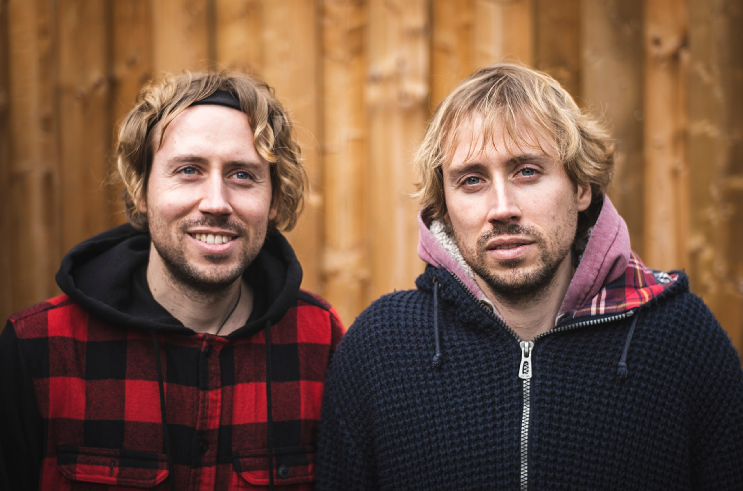 Portrait von USED vor einer Holzwand.