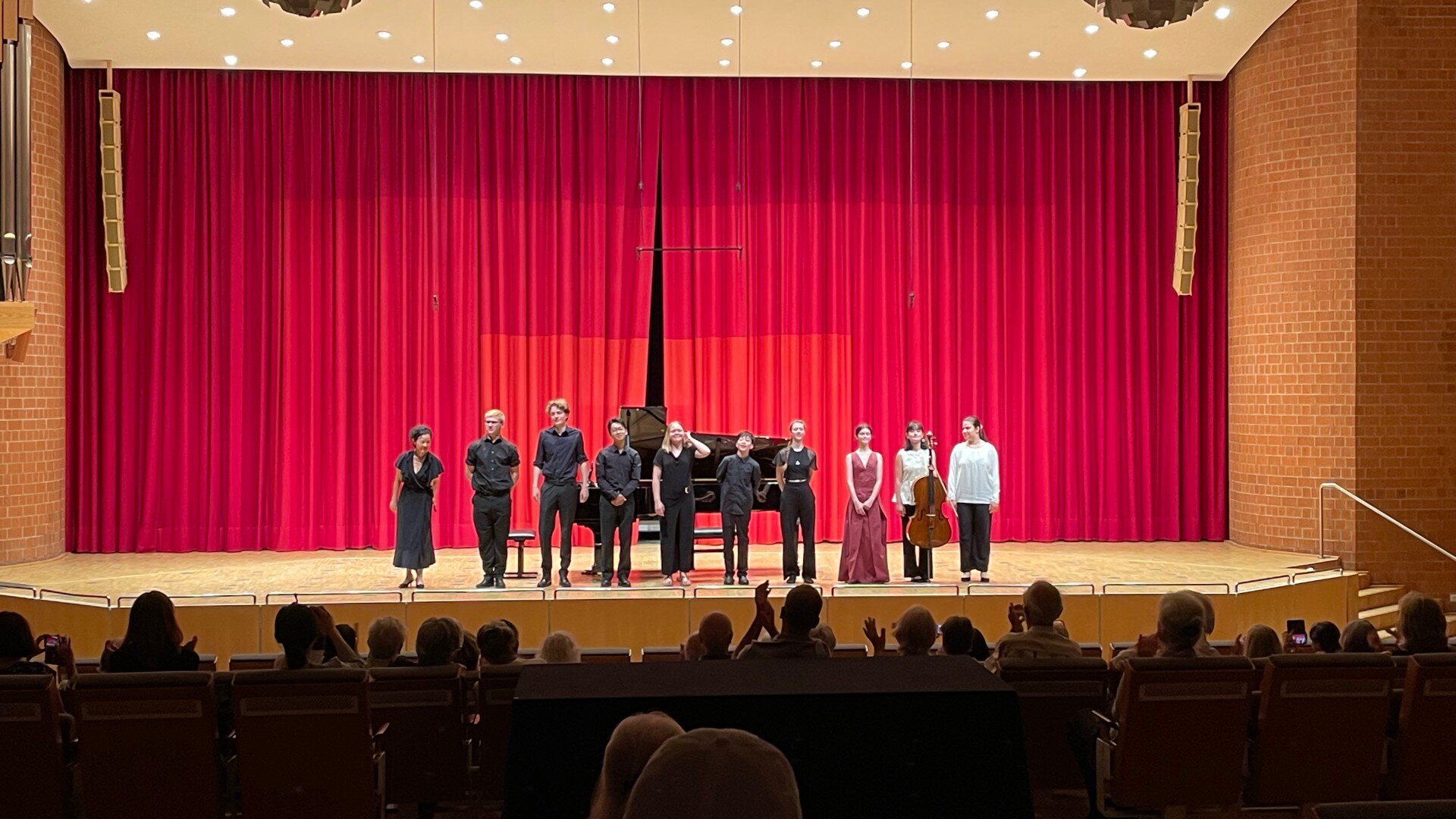 Mitwirkende auf der Bühne vor einem roten Vorhang