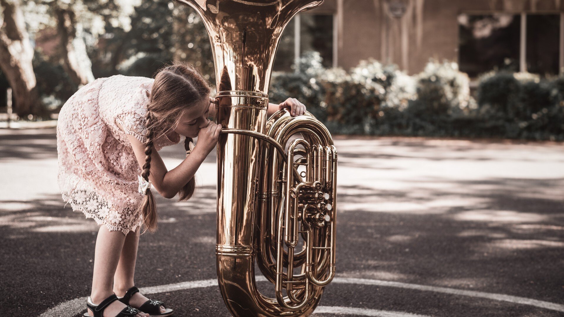 Schulmädchen bückt sich und blast in der auf dem Boden stehenden Tuba