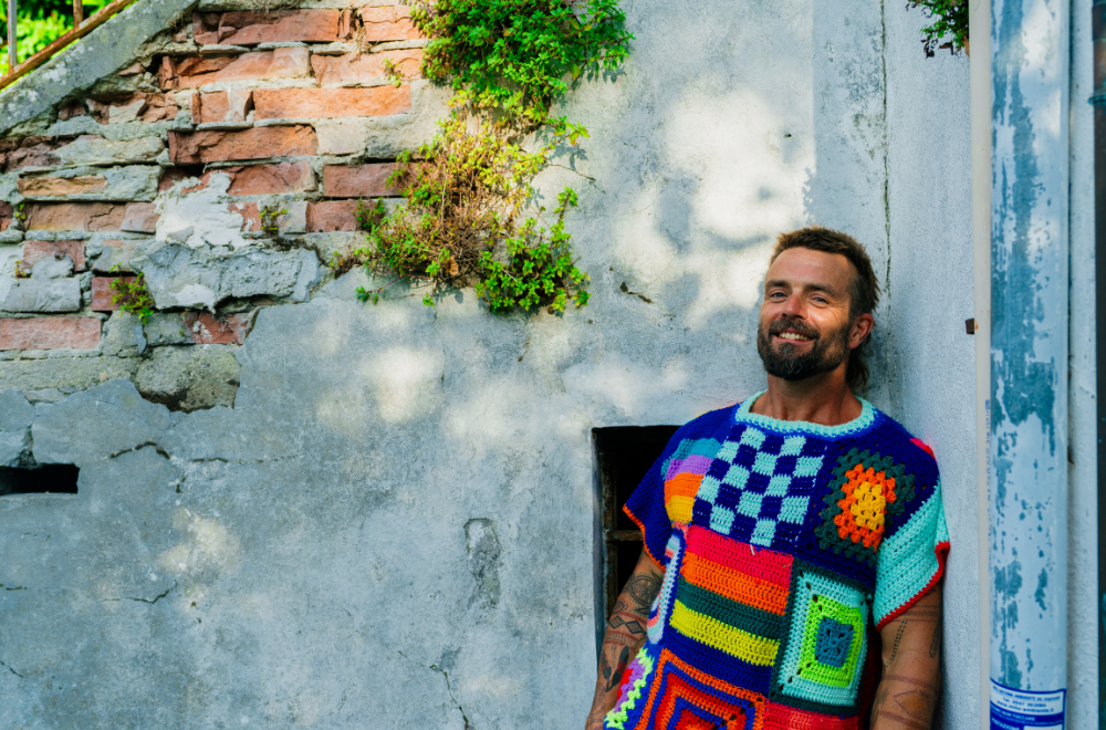 Xavier Rudd ist lässig an eine Außenmauer gelehnt, Sonnenstrahlen streifen sein Gesicht