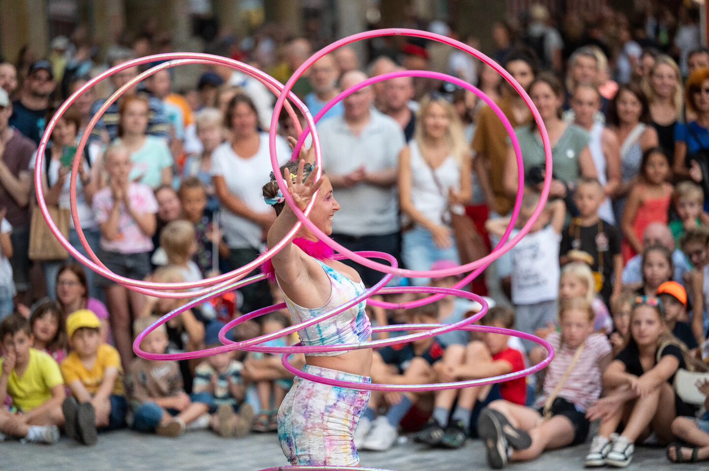 Hoop Boom Boom jongliert mehrere pinke Hula-Hoops auf ihrem Körper.