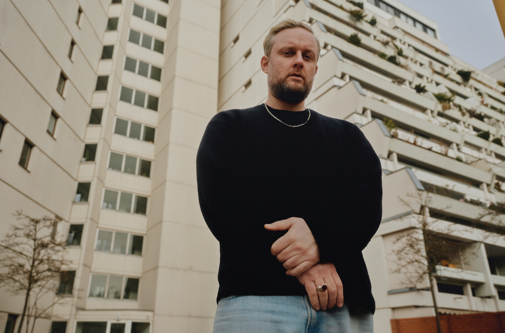 Rapper Fatoni vor einem Blocksiedlungshaus.